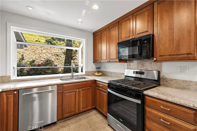 a kitchen with stainless steel appliances a stove a sink a microwave and wooden cabinets