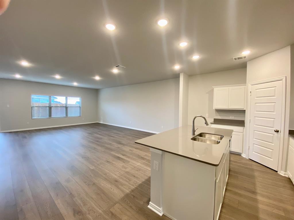615 Metallic Tree Lane Van Alstyne, TX 75495 - Photo 9 of 24 an empty room with wooden floor and kitchen view