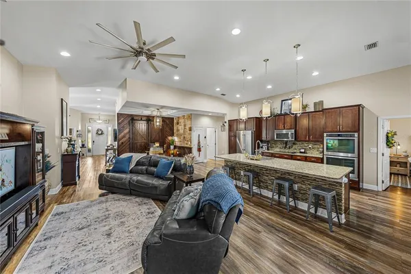 a kitchen with stainless steel appliances granite countertop a kitchen island and chairs in it