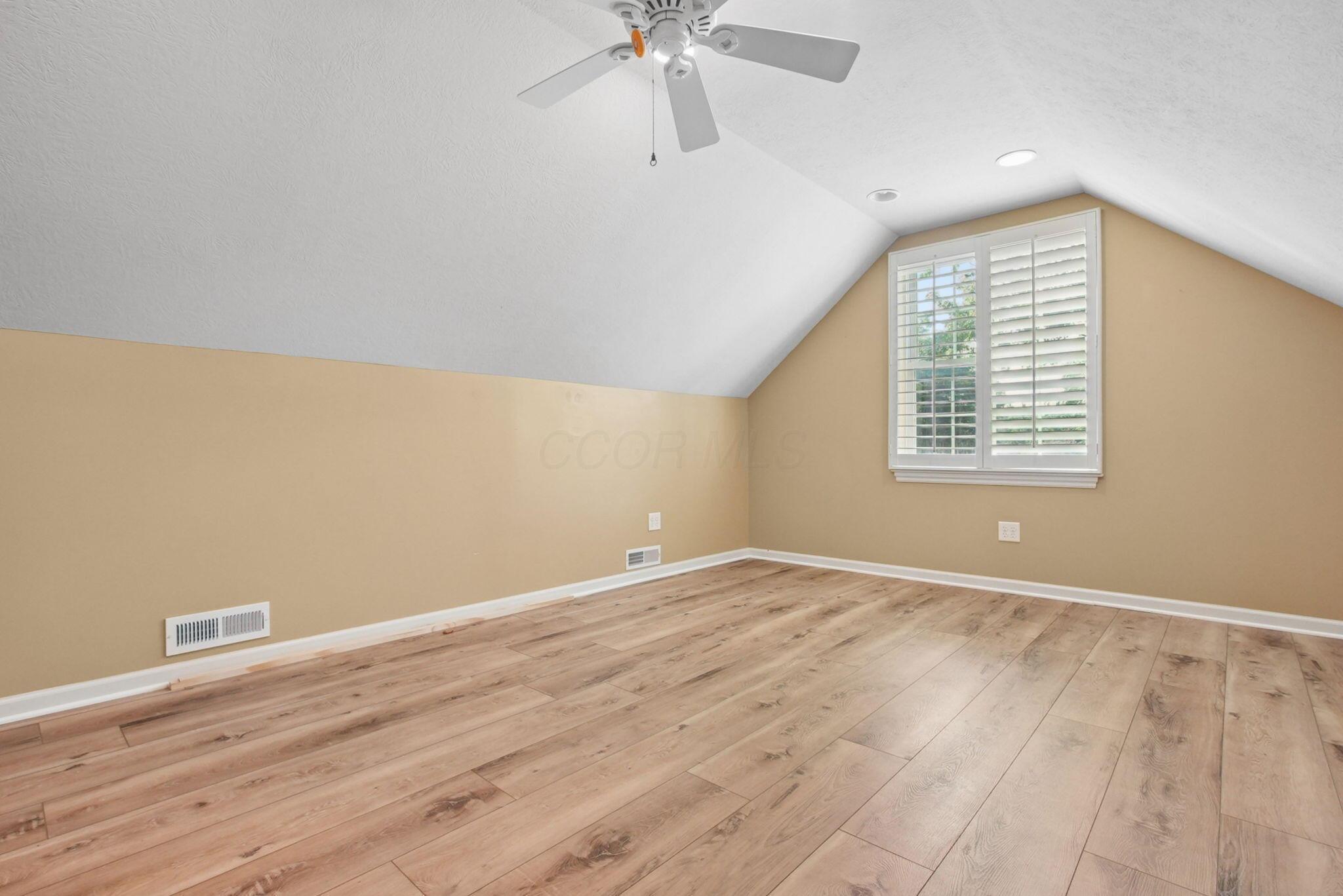 9435 Concord Road Powell, OH 43065 - Photo 39 of 77 Wood-finish flooring, white plantation shutters, vaulted ceiling, ceiling fan, and recessed lighting