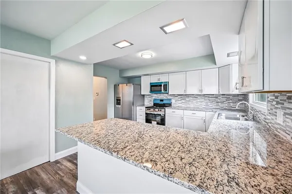 a kitchen with stainless steel appliances granite countertop a refrigerator sink and stove