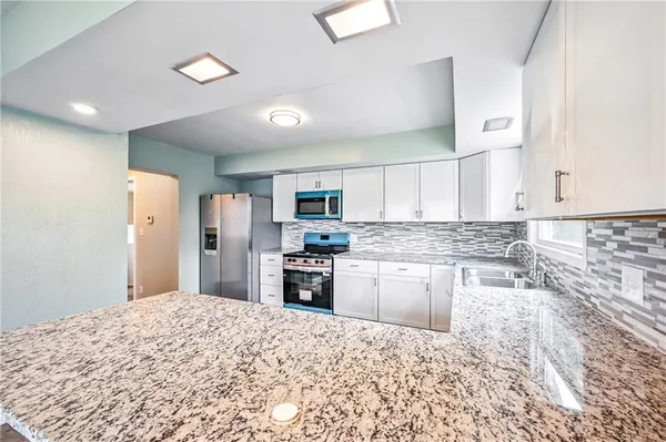 a kitchen with stainless steel appliances granite countertop a stove top oven a sink and dishwasher