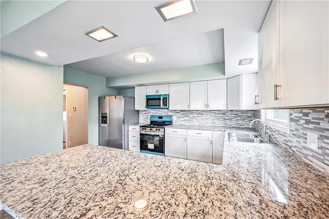 a kitchen with stainless steel appliances granite countertop a stove top oven a sink and dishwasher