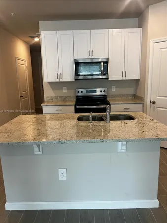 a kitchen with kitchen island a sink a stove and white cabinets