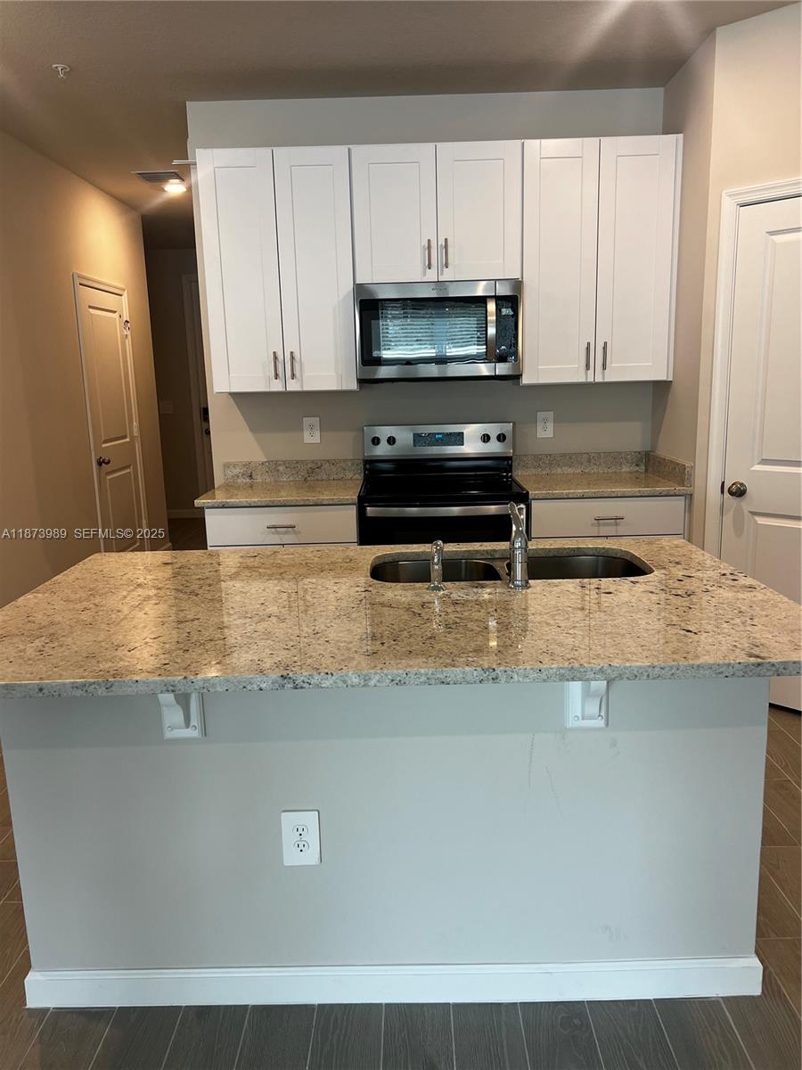 478 Salisbury Circle Fort Pierce, FL 34982 - Photo 5 of 11 a kitchen with kitchen island a sink a stove and white cabinets