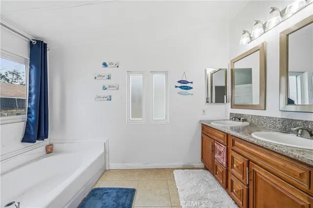 a bathroom with a granite countertop tub sink and mirror