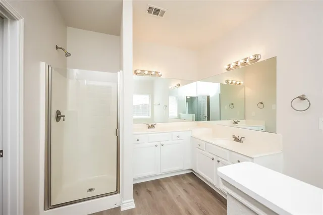 a bathroom with a double vanity sink a mirror a bathtub and shower