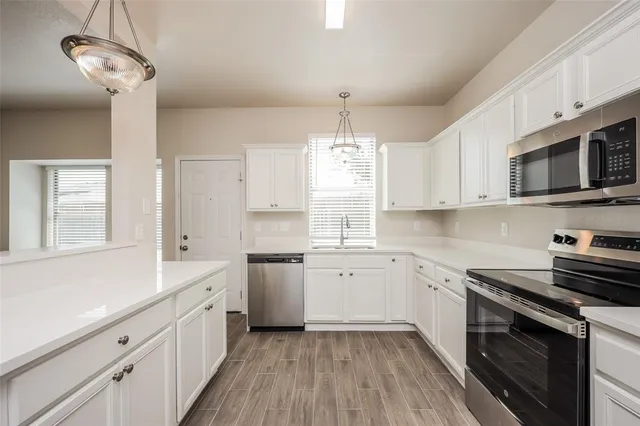 a kitchen with a sink stove cabinets and wooden floor