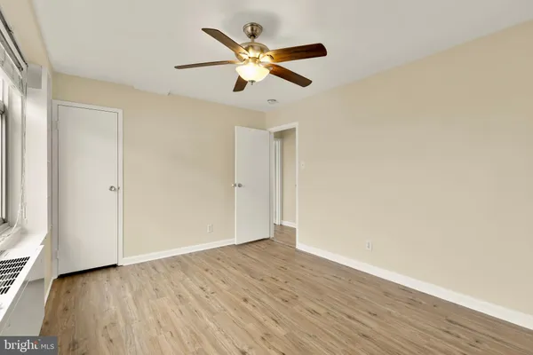 an empty room with wooden floor and a ceiling fan