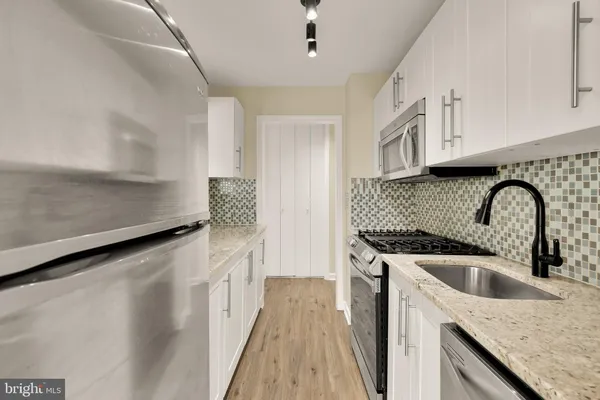 a kitchen with stainless steel appliances granite countertop a sink a stove and a refrigerator