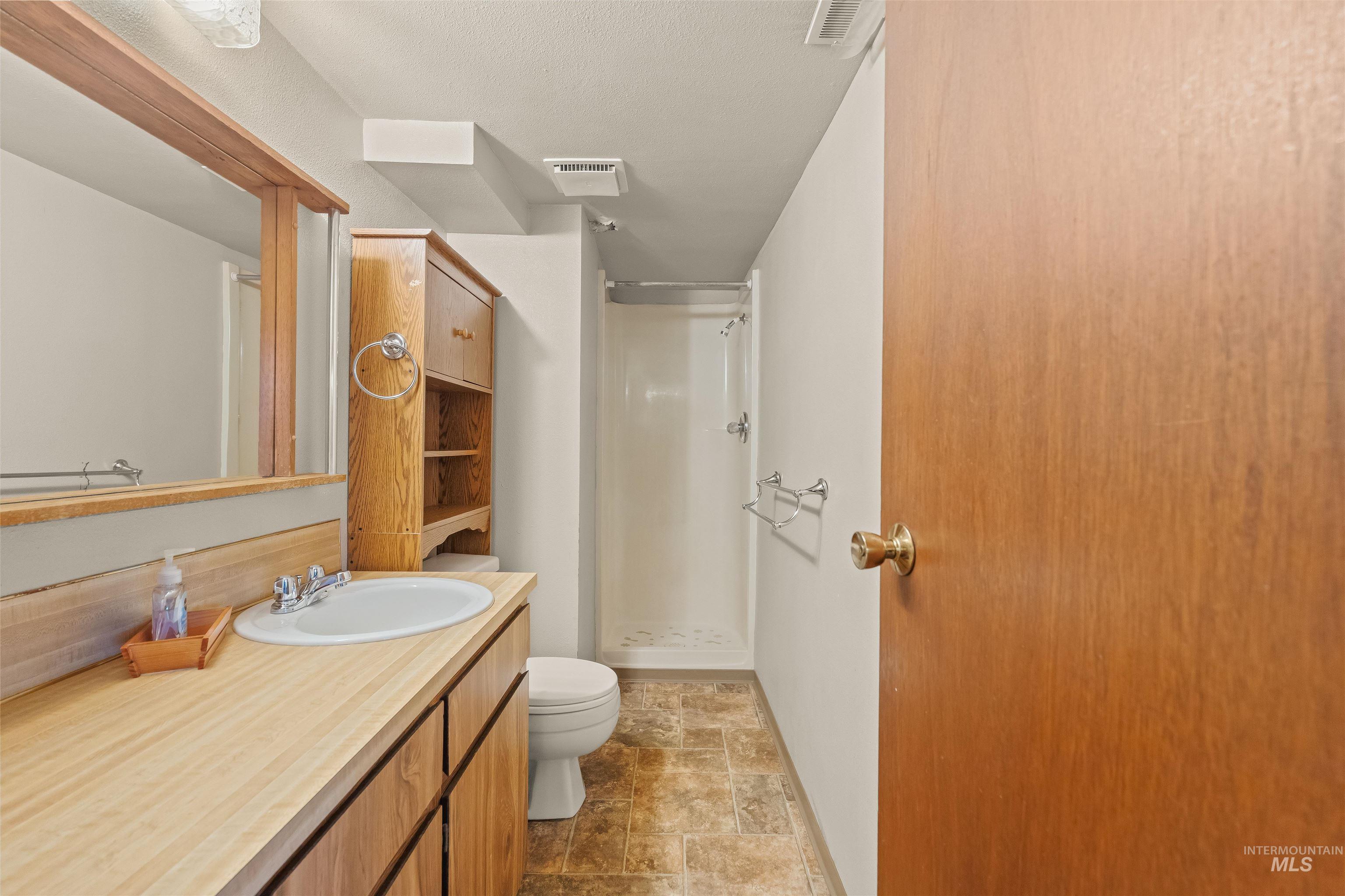 1663 9th Avenue Lewiston, ID 83501 - Photo 15 of 36 Full bathroom featuring a wood-finish vanity with an integrated sink, a large wall-mounted mirror, a built-in shower stall, and patterned floor tiling