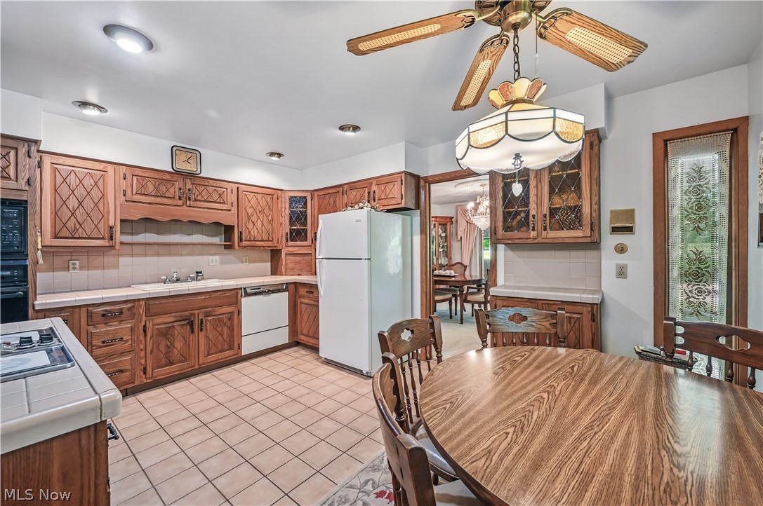 2717 Niles Vienna Road Niles, OH 44446 - Photo 13 of 50 Kitchen with white appliances, tile counters, backsplash, brown cabinets, and a ceiling fan