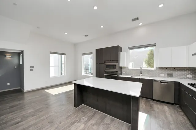 a open kitchen with kitchen island a sink dishwasher a stove and a refrigerator with wooden floor