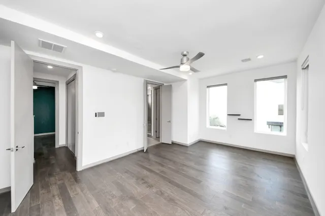 an empty room with wooden floor and windows