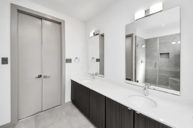 a bathroom with a double vanity sink mirror and shower