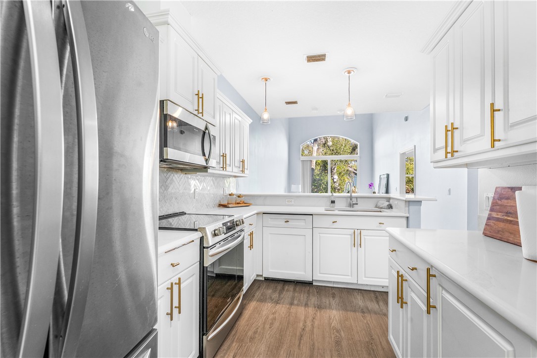 909 Bahia Mar Road Vero Beach, FL 32963 - Photo 14 of 36 a kitchen with stainless steel appliances granite countertop a sink cabinets a stove and a refrigerator