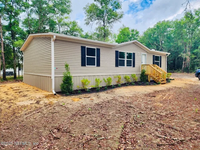 a front view of a house with a yard and potted plants