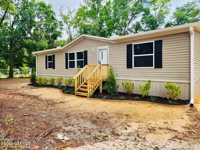 a view of a house with a yard and potted plants