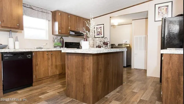 a living room with stainless steel appliances furniture a flat screen tv and a window