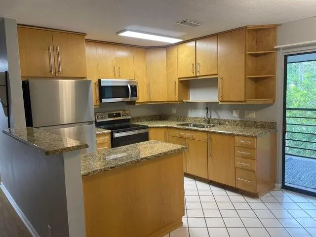 a kitchen with stainless steel appliances granite countertop a refrigerator a stove a sink and a microwave