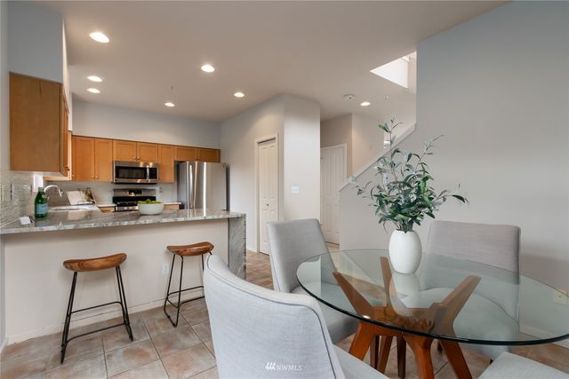 a kitchen with stainless steel appliances granite countertop a dining table chairs and granite counter tops