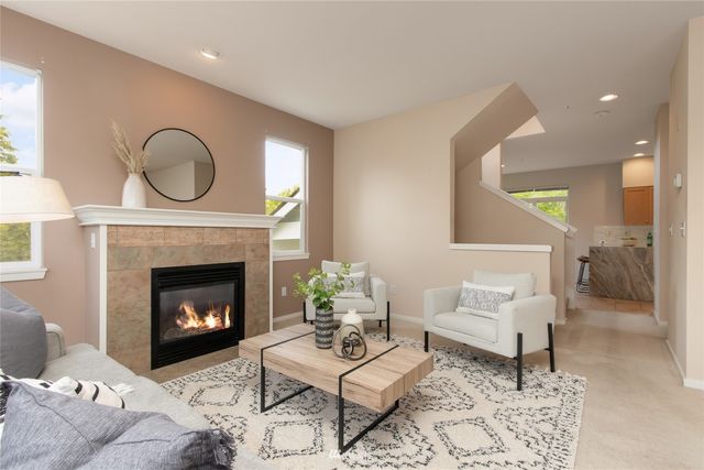 a living room with furniture a fireplace a rug and a window