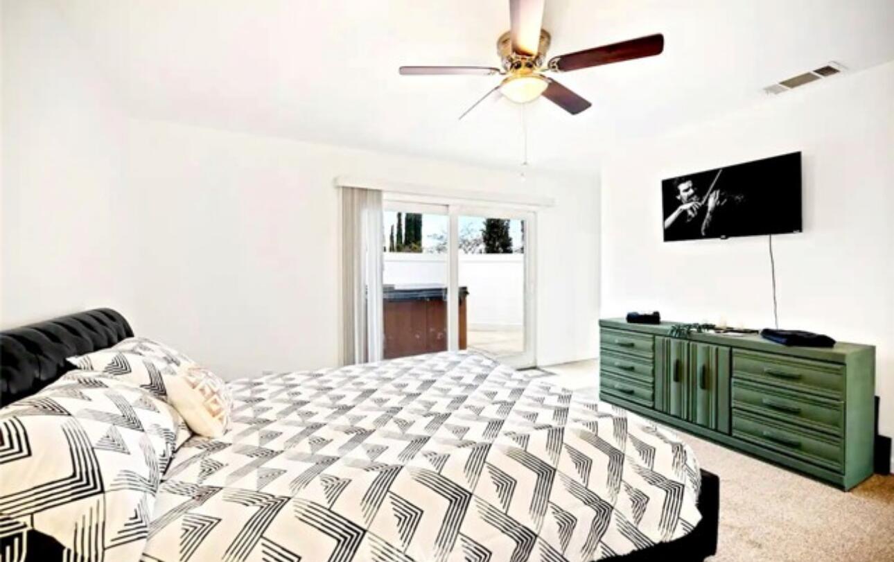 8564 Taft Court Yucca Valley, CA 92284 - Photo 12 of 25 a bedroom with a bed a flat screen tv and a ceiling fan