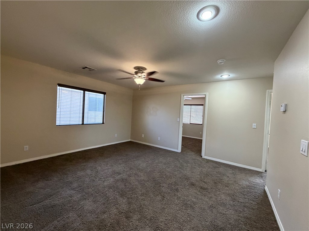 7613 Roop Street Las Vegas, NV 89131 - Photo 12 of 25 A spacious carpeted living area features recessed lighting and an adjoining doorway leading to another room.