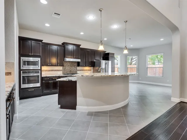 a kitchen with stainless steel appliances granite countertop a refrigerator a sink a stove a microwave and island