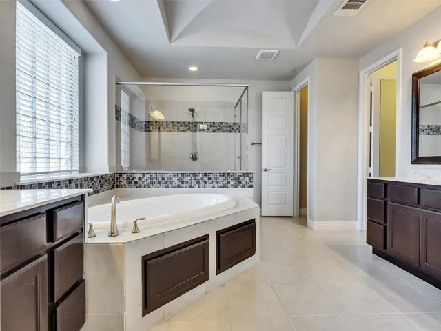 a bathroom with a tub a sink and mirror
