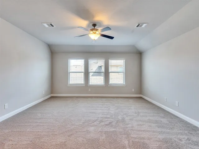 an empty room with chandelier fan and windows