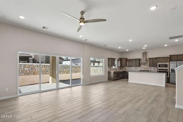 a large kitchen with stainless steel appliances wooden floor and a large window
