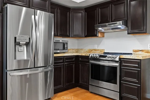 a kitchen with stainless steel appliances granite countertop a stove a sink dishwasher a refrigerator and a microwave oven