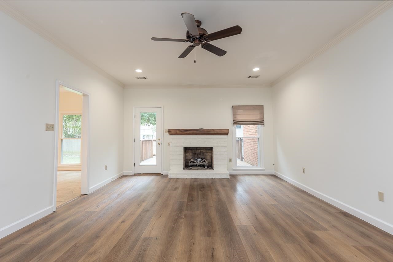 759 West Powell Road Collierville, TN 38017 - Photo 22 of 39 an empty room with windows a fireplace a ceiling fan and wooden floor