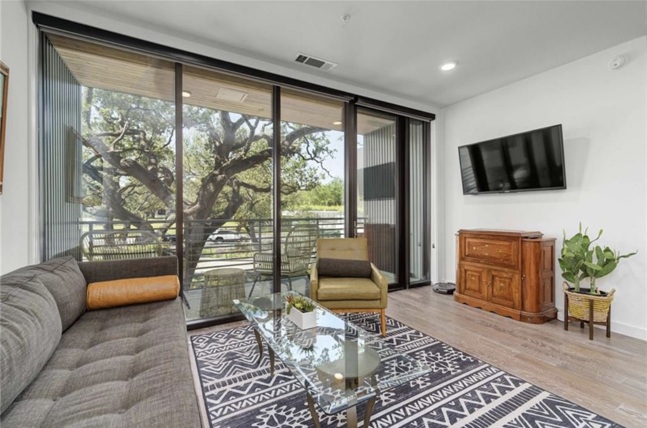 900 South 1st Street, Unit 304 Austin, TX 78704 - Photo 1 of 22 a living room with furniture a flat screen tv and a floor to ceiling window