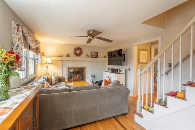 a living room with furniture a fireplace kitchen view and a large window