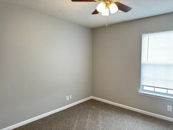 an empty room with a window and a chandelier fan