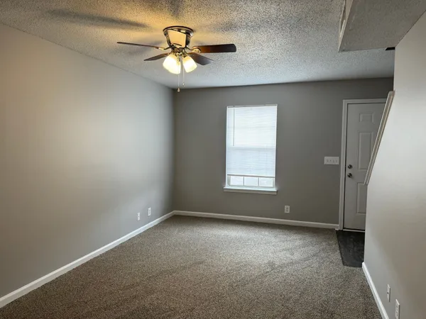 an empty room with a window and a fan