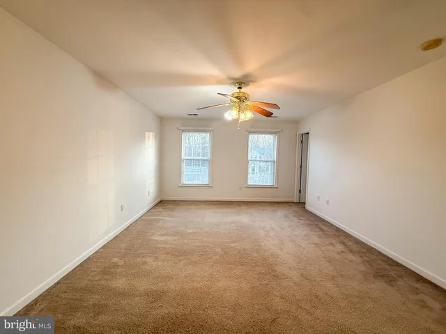 an empty room with windows and chandelier fan