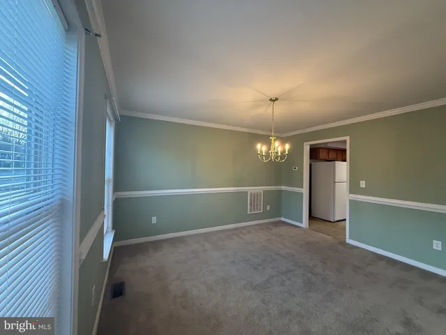 an empty room with chandelier fan and windows