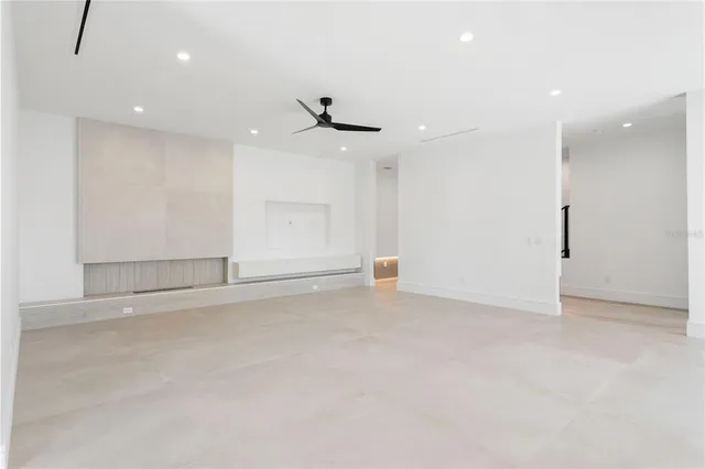 an empty room with ceiling fan and windows