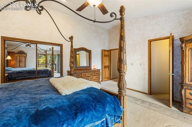 a spacious bedroom with a bed a mirror and windows