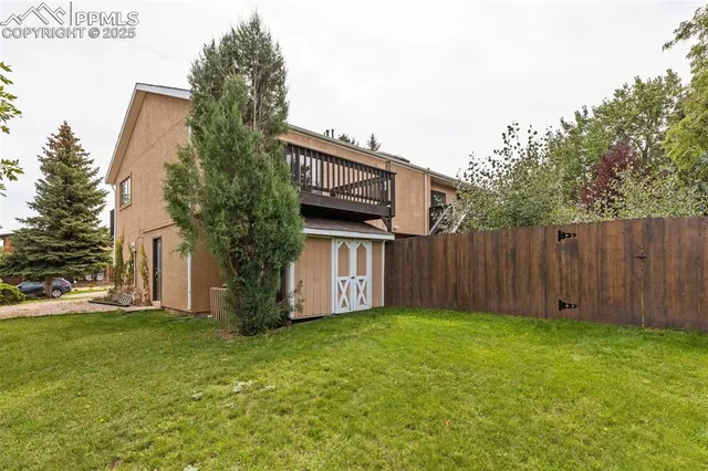 a view of a house with backyard and wooden fence