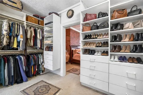 a view of walk in closet with clothes and shoes