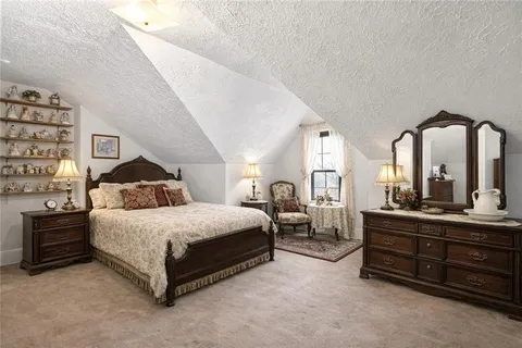 a spacious bedroom with a bed a mirror and lamp on table