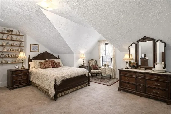 a spacious bedroom with a bed a mirror and lamp on table