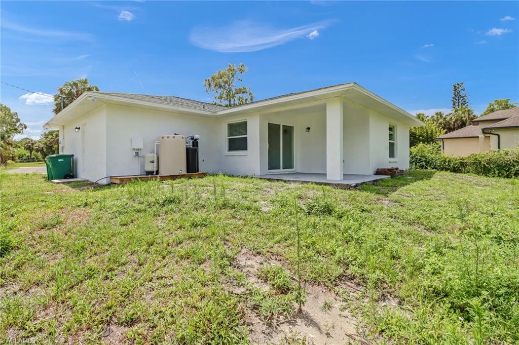 981 11th Street Southwest Naples, FL 34117 - Photo 3 of 24 Back of property with a lawn and a patio area