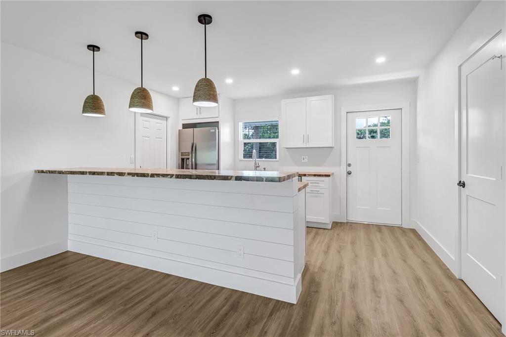 981 11th Street Southwest Naples, FL 34117 - Photo 5 of 24 Kitchen featuring pendant lighting, light hardwood / wood-style flooring, kitchen peninsula, stainless steel refrigerator with ice dispenser, and white cabinetry