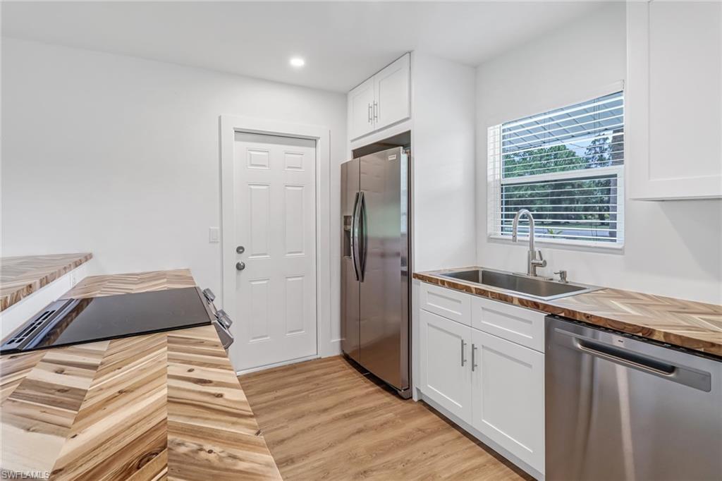 981 11th Street Southwest Naples, FL 34117 - Photo 6 of 24 Kitchen featuring white cabinets, wooden counters, sink, light hardwood / wood-style flooring, and appliances with stainless steel finishes