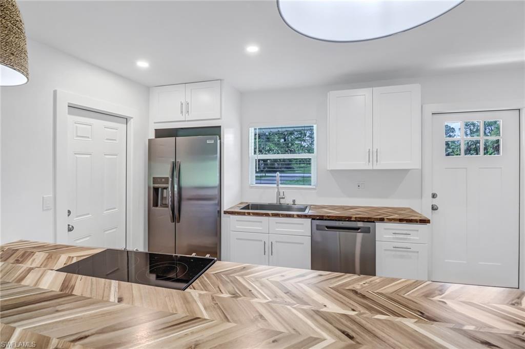 981 11th Street Southwest Naples, FL 34117 - Photo 7 of 24 Kitchen with plenty of natural light, sink, wood counters, appliances with stainless steel finishes, and white cabinetry